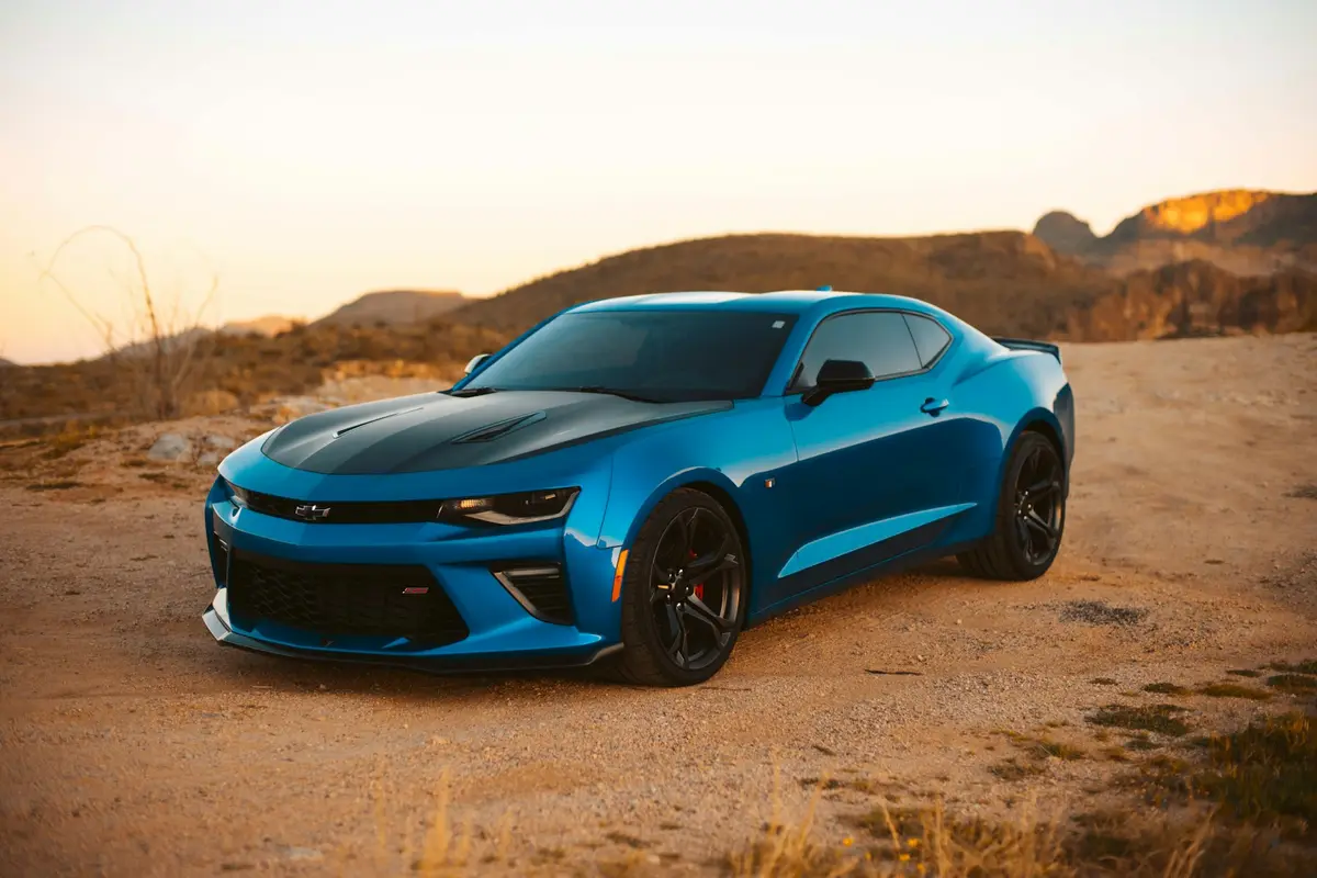 Blue Chevrolet Camaro SS, three-quarter front view in golden-hour desert light