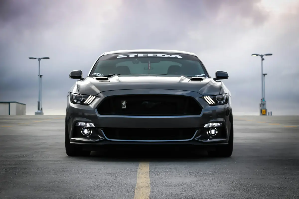 Grey Ford Mustang GT head-on under a stormy sky on an empty rooftop lot — delivered grade